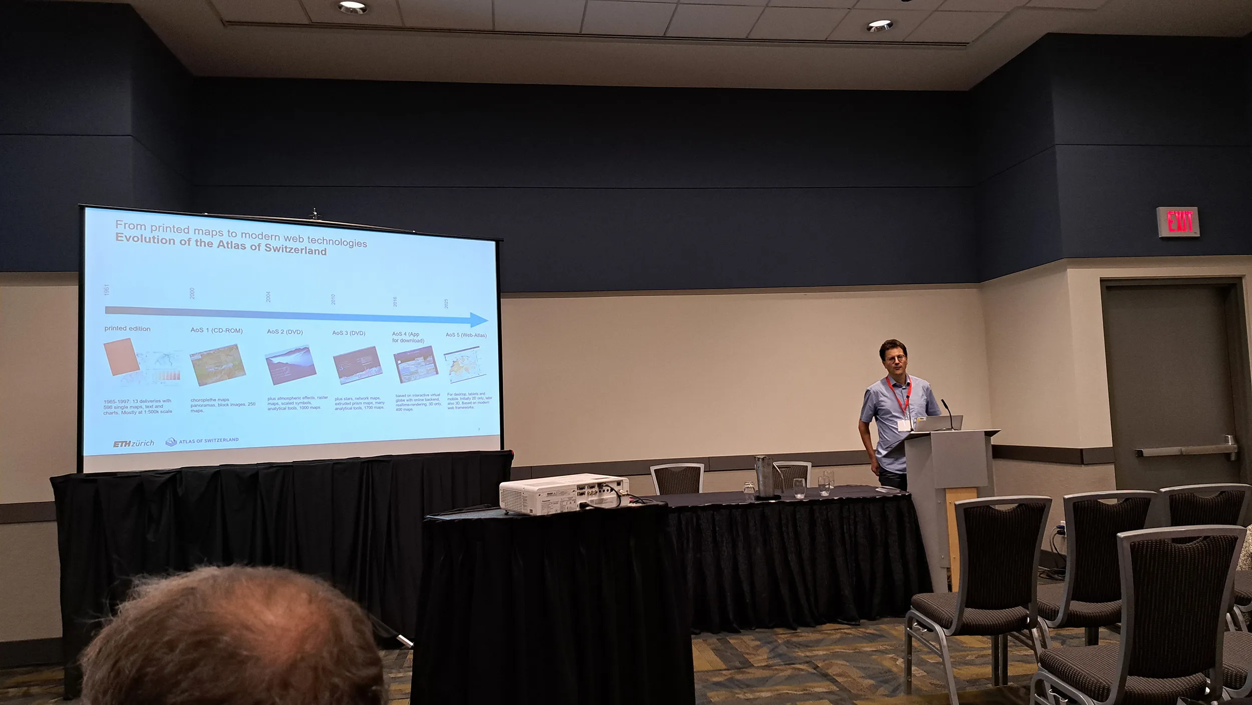 Un homme présente l’« Atlas de la Suisse » dans une salle de conférence.