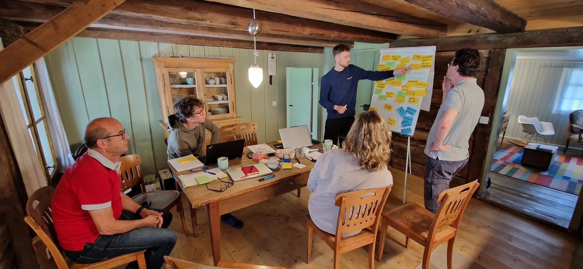 Atelier de groupe dans une pièce rustique avec un tableau à feuilles et des post-it.