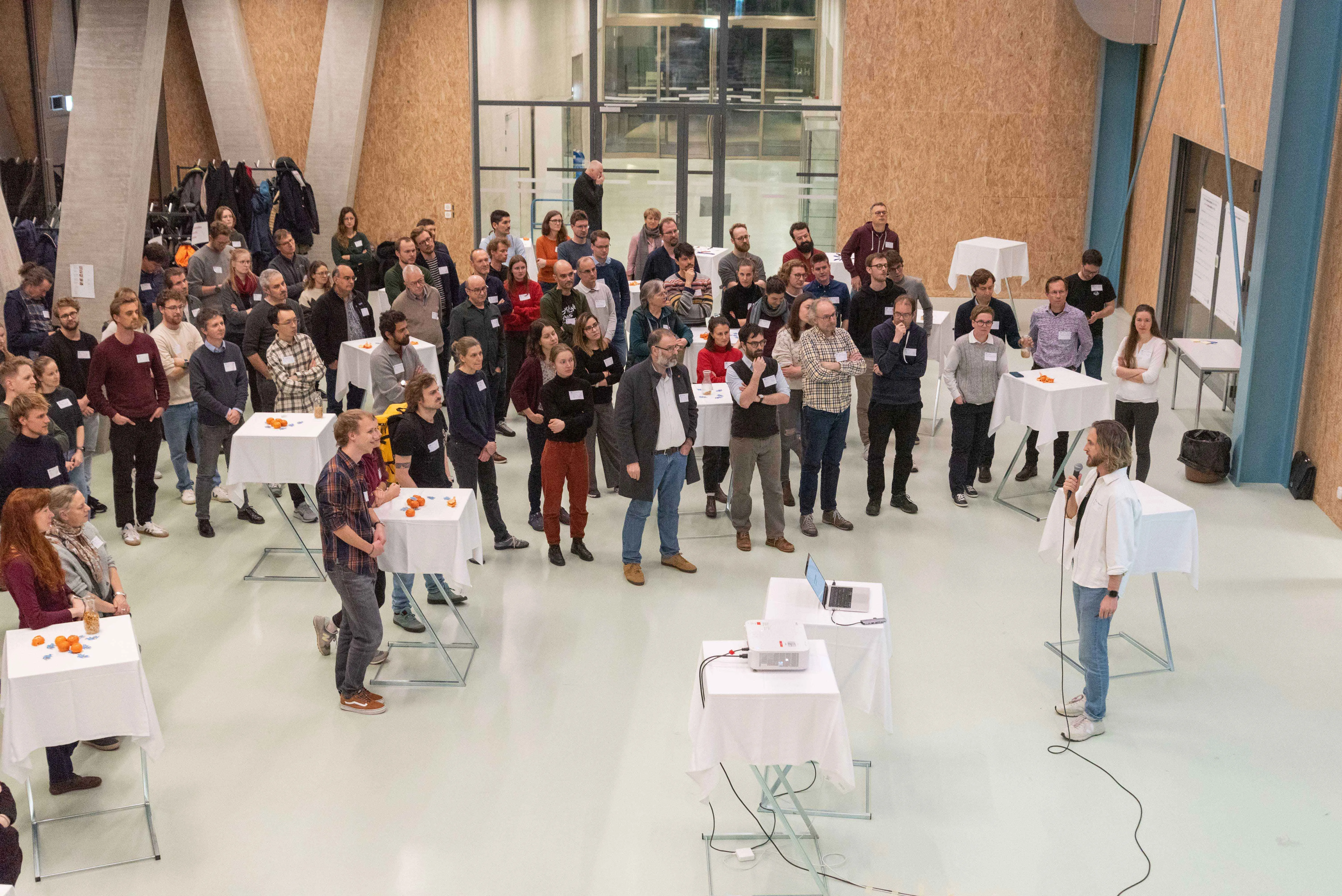 Un groupe de personnes se tient debout dans une salle d'événement et écoute un orateur